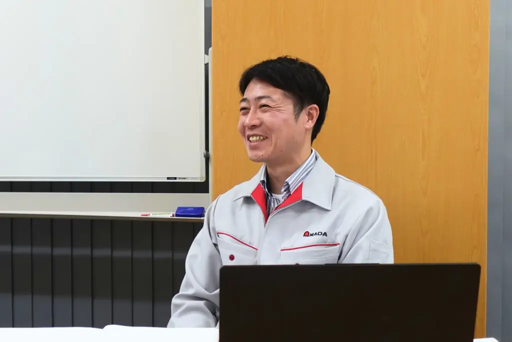 作業着の担当者が笑顔で語るインタビュー。運用面の使い勝手や社内展開の手応えを述べるシーン。