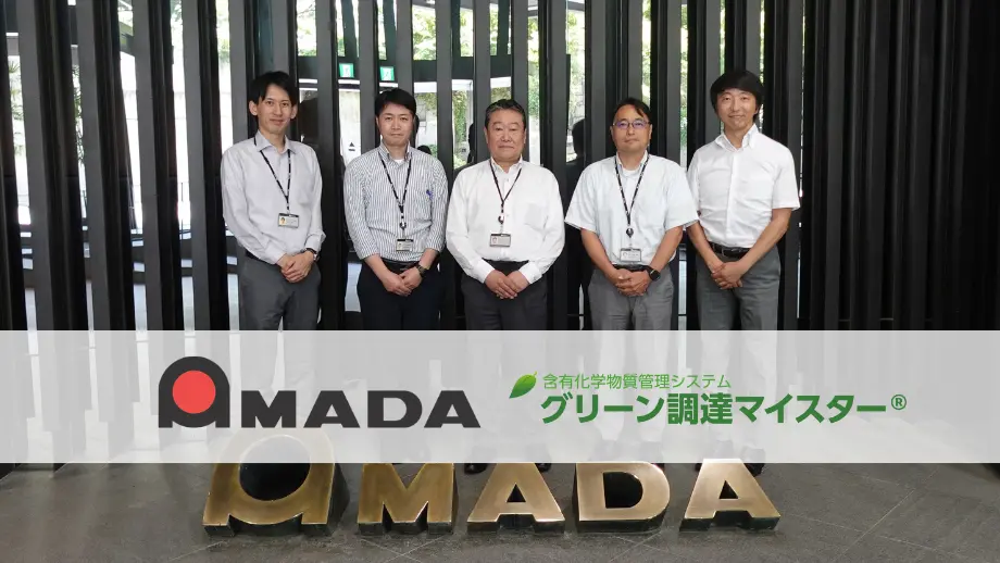 アマダ本社エントランスで5名が並ぶ集合写真。含有化学物質管理システム「グリーン調達マイスター」導入事例のサムネイル。