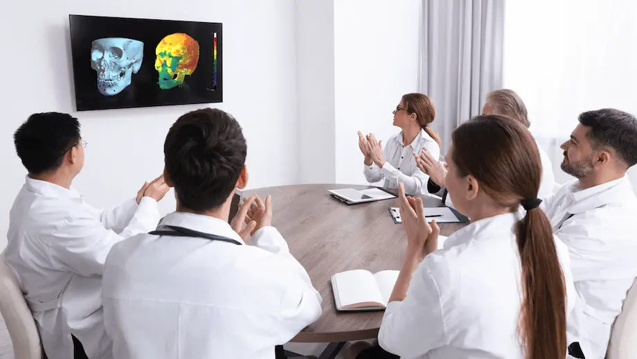 歯科医師チームが3D頭蓋骨解析画像をモニターで確認しながら会議を行っている様子