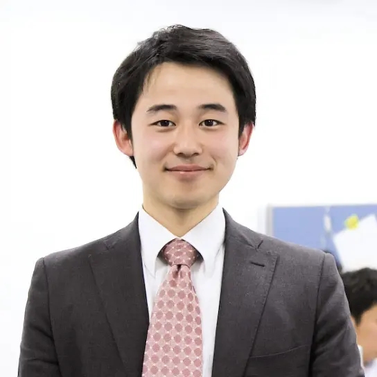 スーツ姿で微笑む若手男性社員の正面ポートレート。