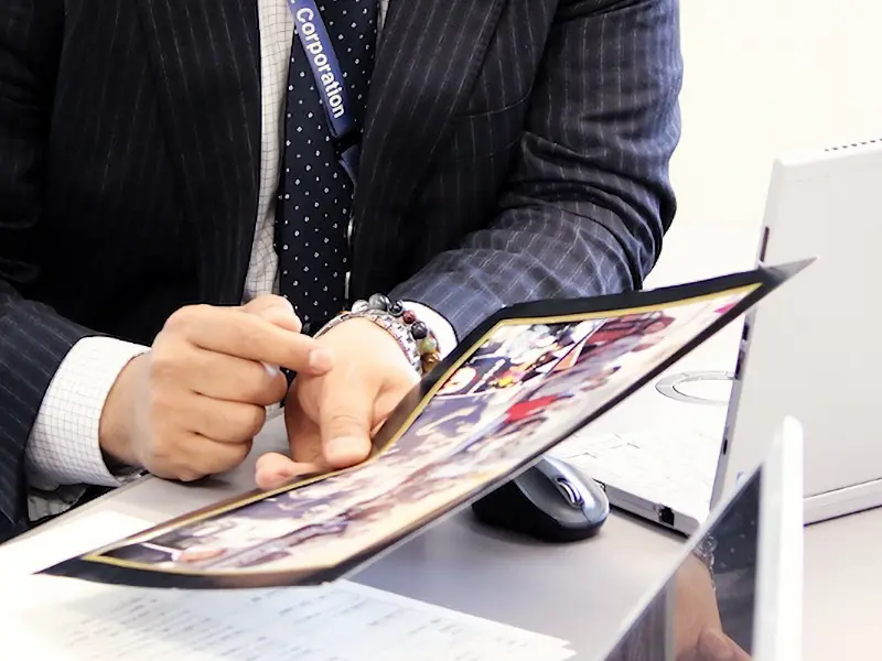 プレゼン資料を指し示しながら説明する坂本さんの手元。腕時計がアクセントとなり、動きが伝わる。