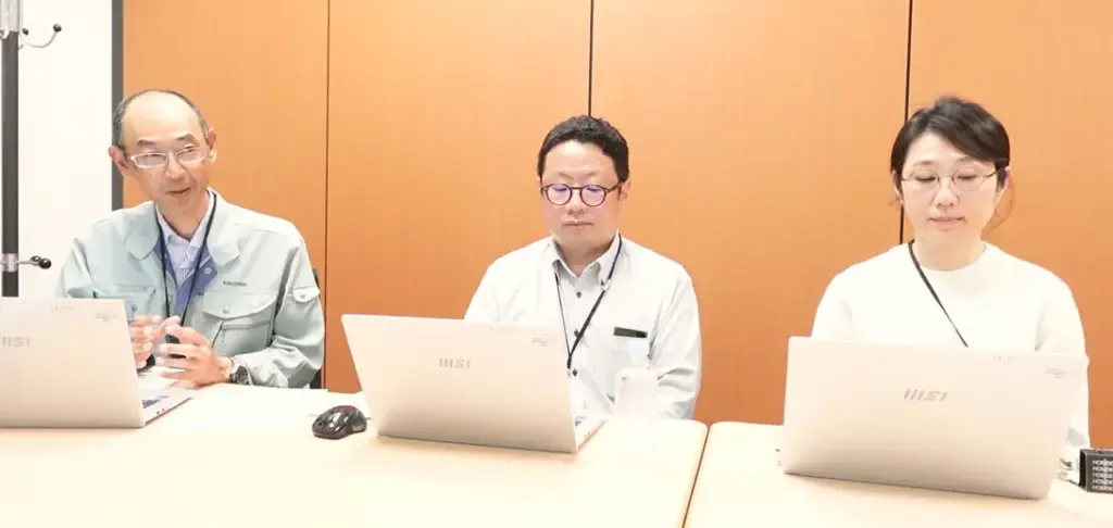 グリーン調達マイスター活用について語る加賀マイクロソリューション担当者3名がノートPCを前にインタビューを受けているシーン。