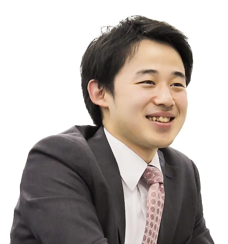 インタビュー用に切り抜かれた丸山さんの上半身カット、スーツ姿で親しみやすい表情。