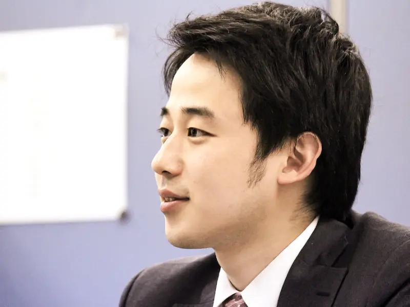 若手社員インタビューで、横顔を映しながら真剣に語る丸山さんのクローズアップ。