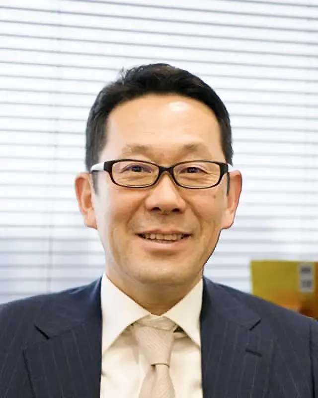 会社案内用プロフィールとして撮影された、眼鏡をかけ笑顔を見せる社長のバストアップ写真。