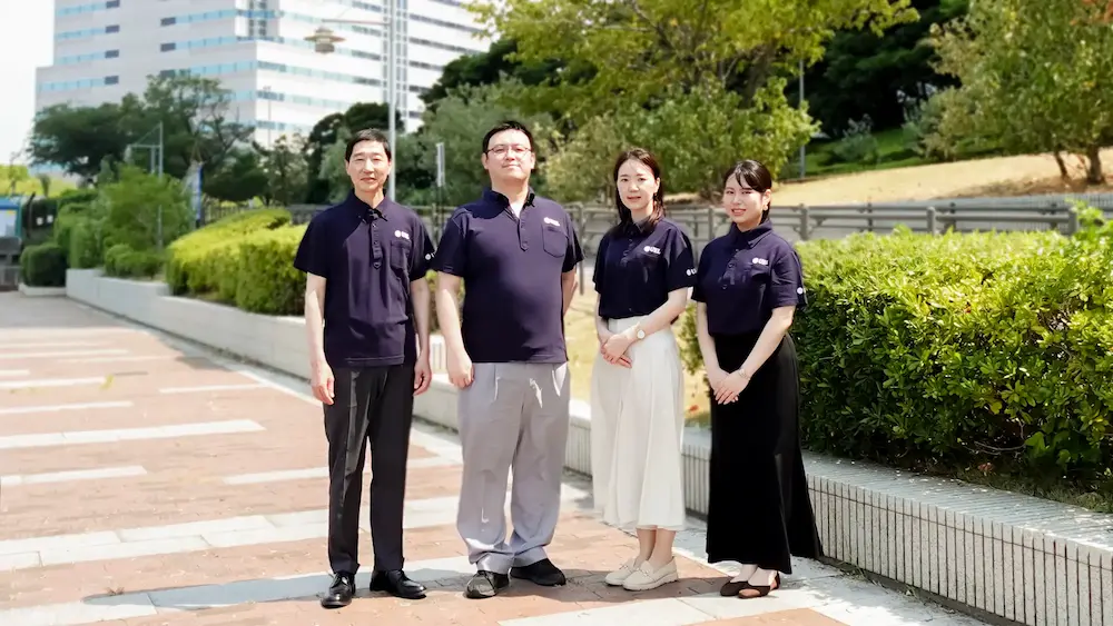 UELのスタッフ4名が屋外で並んでいる集合写真